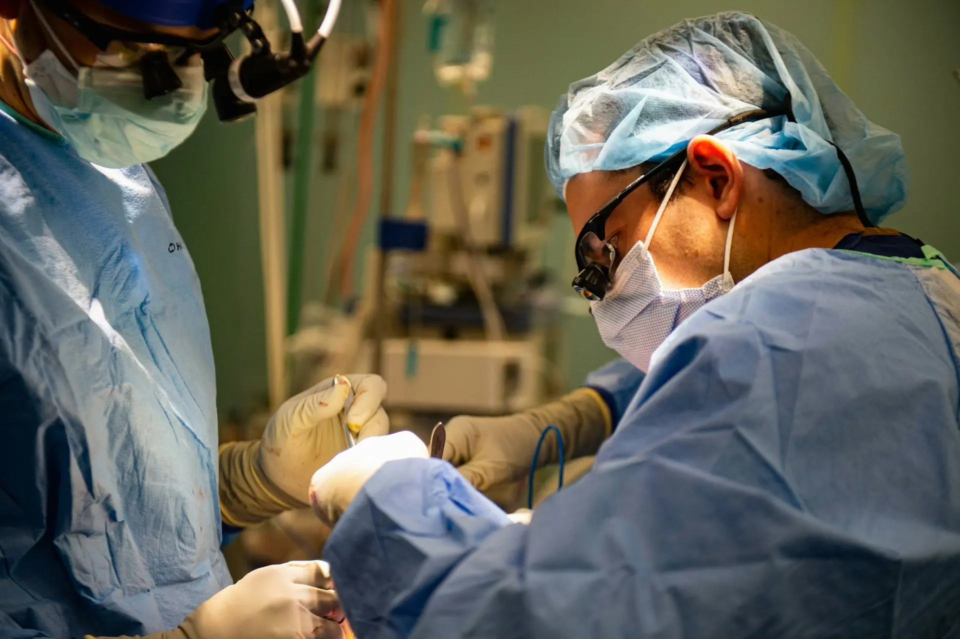 Surgeons in sterile gowns performing a medical operation.